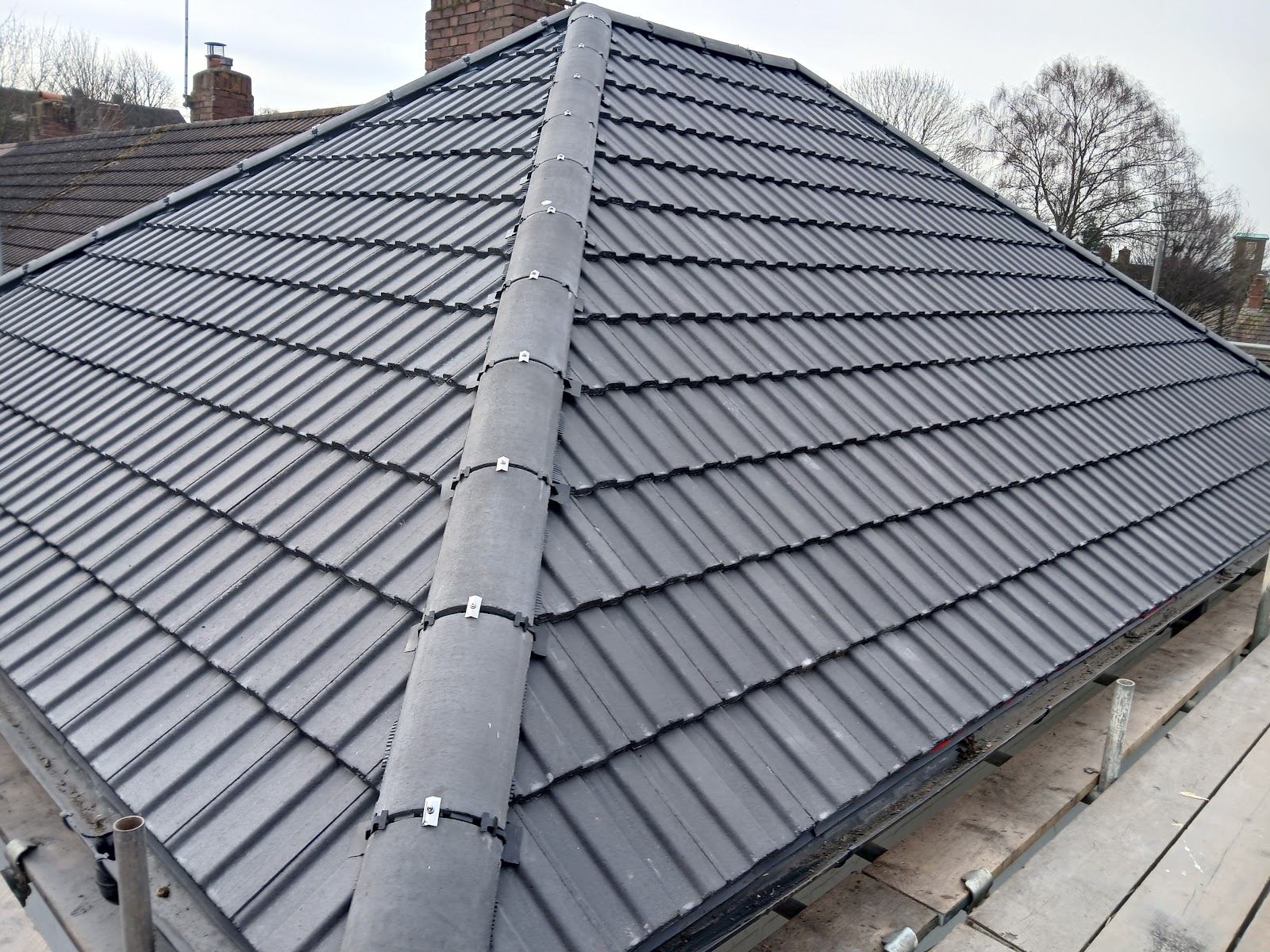 A finished grey tiled hip roof, cleanly re-roofed on an Exeter home