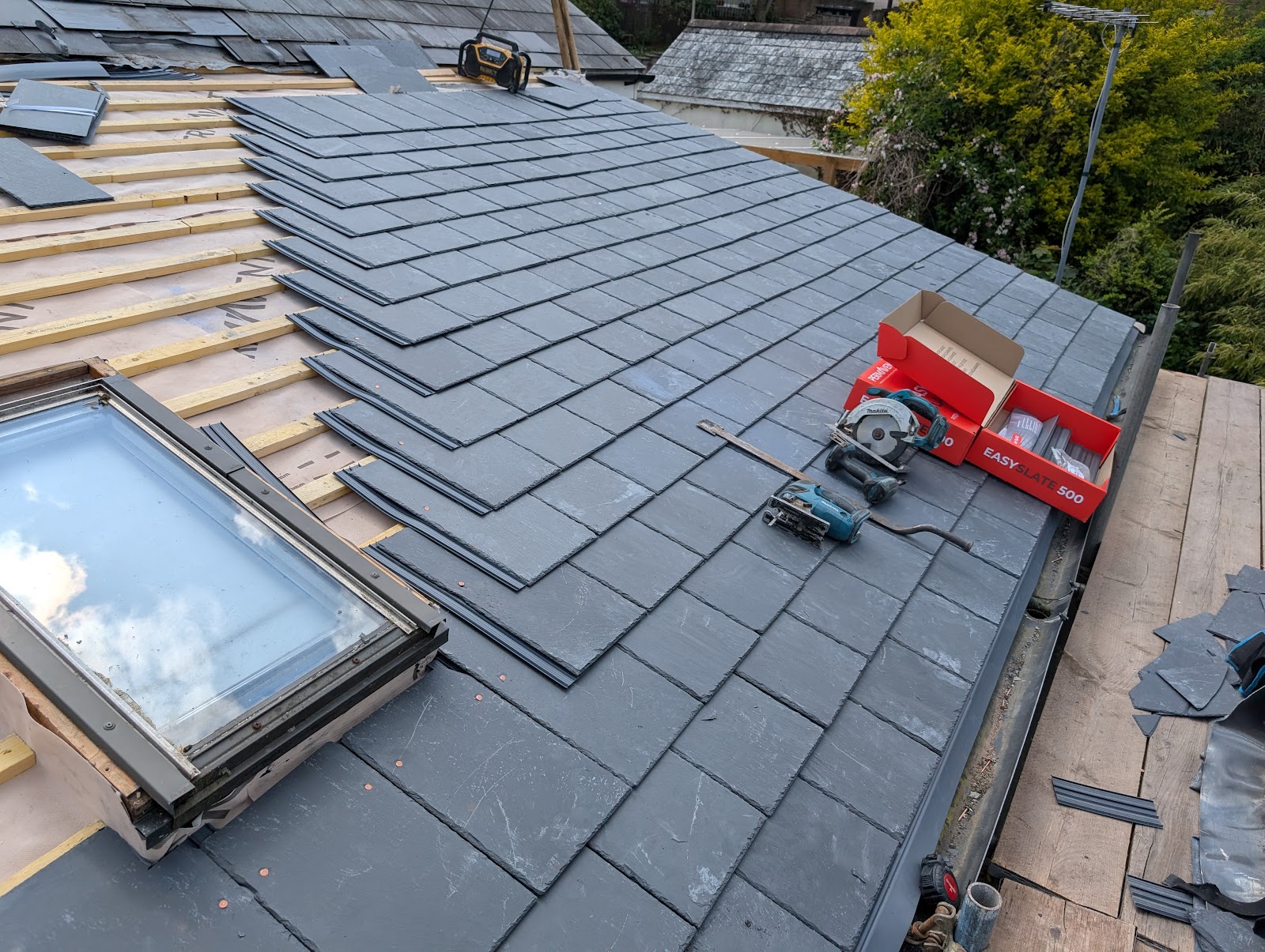 New slate tiles being laid around a skylight during a roof re-lay