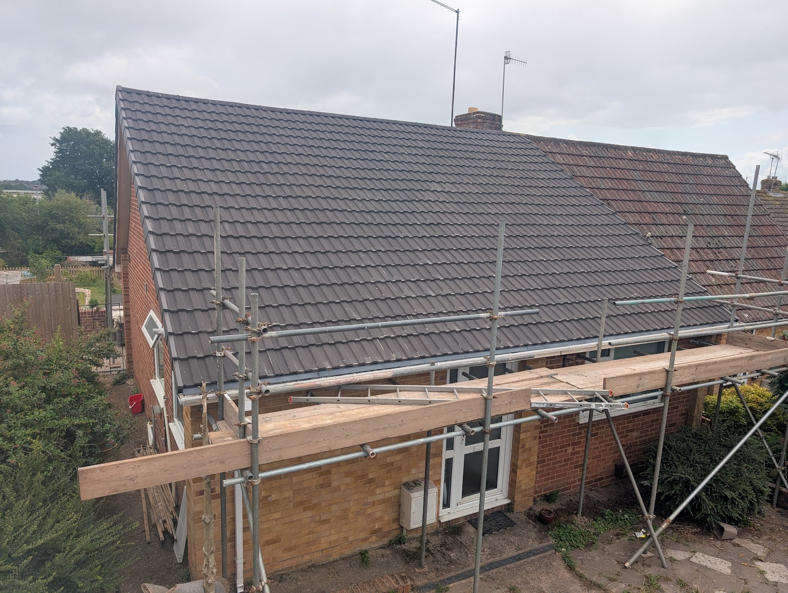 A completed tiled roof replacement on a Devon property with scaffold still up